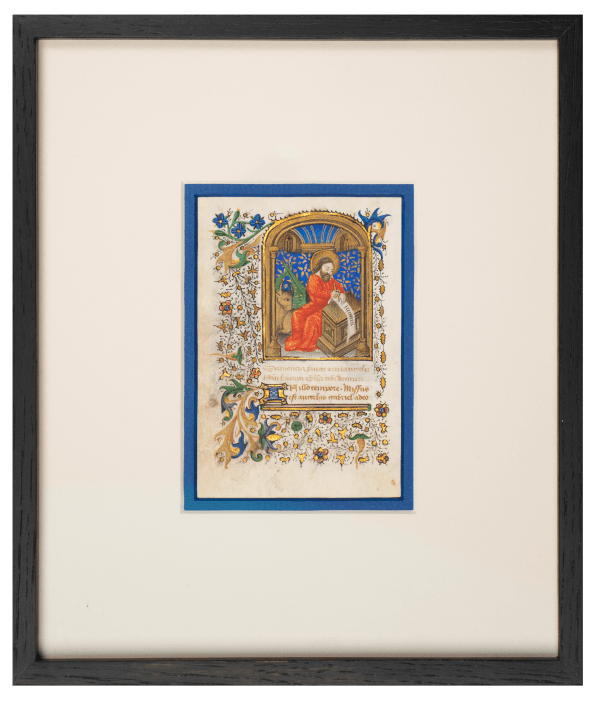 Medieval illuminated manuscript miniature featuring Saint Luke the Evangelist, depicted with a golden halo and red robes within an ornate Gothic architectural frame. The folio is decorated with elaborate marginalia including colorful foliate scrollwork in gold, blue, and green, small flowers, and decorative borders. Latin text appears below the miniature. The artwork demonstrates typical 15th-century manuscript illumination techniques with gold leaf, vibrant pigments, and intricate decorative elements. Artwork by the Master of the Vienna Roman de la Rose. La Gabrielle Fine Arts SA, Geneva.