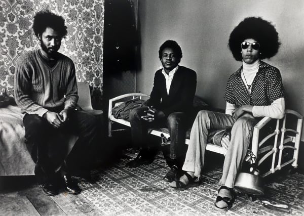 Colin Jones, The Black House, three men pose sat on a bed, Holloway road, London 1973 - 1976