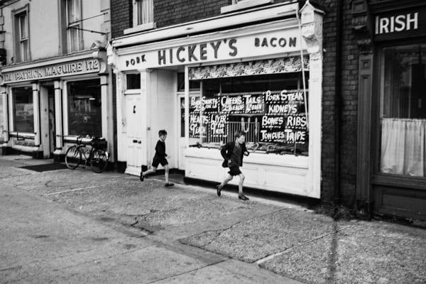 Edward Quinn, Boys running past Hickey’s, Dublin 1963