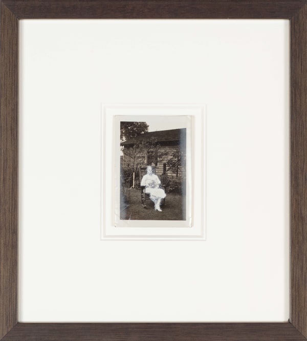 John Latour, Serious woman in white holding cat and seated in yard, 2008