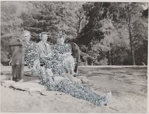 John Latour, Two women with crossed legs sit on either side of a man on a bench. A second man stretches out on the lawn, at their feet. Everyone is smiling, 2020