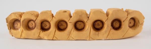 A sculpture of a segmented block with a circular detail in the side of each segment by artist Reniel Del Rosario.