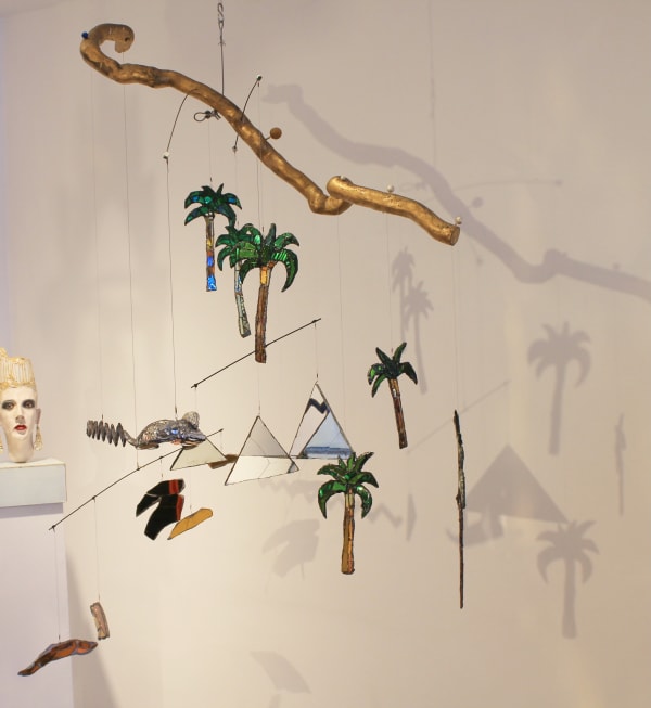 A colourful, glittering sculpture by Andrew Logan inspired by ancient Egypt, featuring gold, mirrors, and jewel-like decorations shaped like pyramids and palm trees.