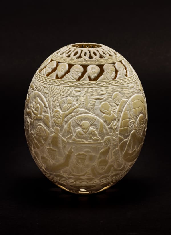Intricately carved ostrich egg with depiction of judges, prisoners police, and aliens