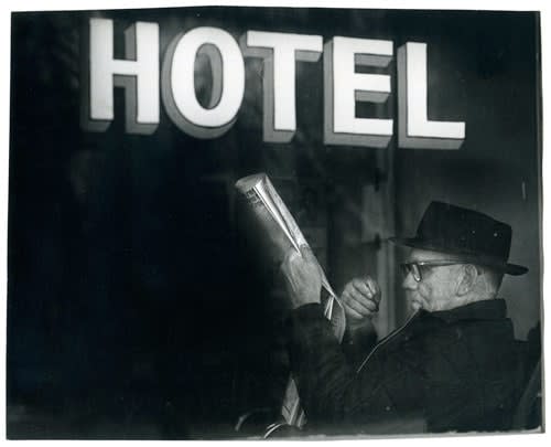 ENLARGEMENT REPRINT Vernacular, Untitled (Man reading a newspaper, under Hotel sign), Neg. Date: 1979