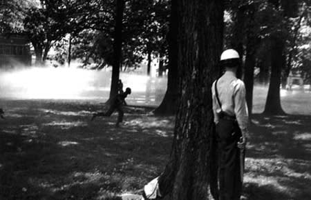 Bruce Davidson, Untitled [policeman hides while protestors are hosed], Birmingham, AL, A Time of Change, 1963