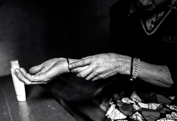 Alice Kayibanda, Life in the shadow-Nyirahabimana Belina applying sunscreen on her hands, 2020