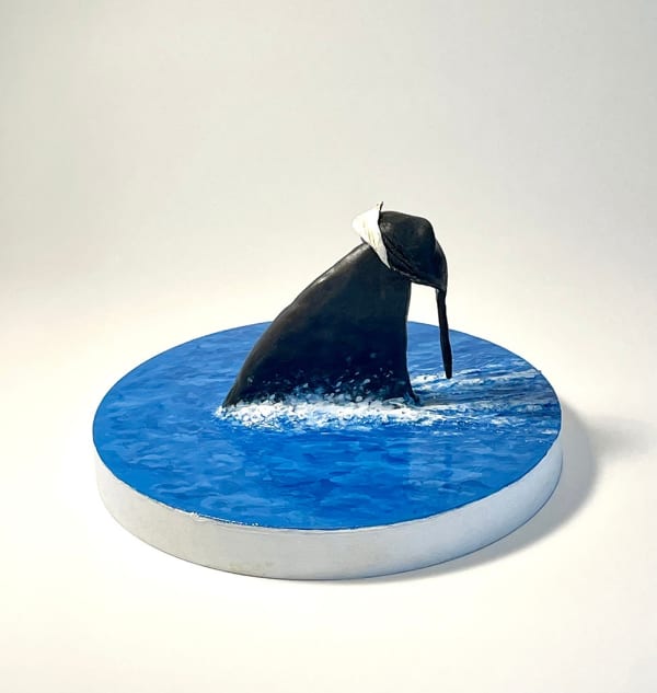 sculpture of a shark fin swimming through water with a hat on its fin