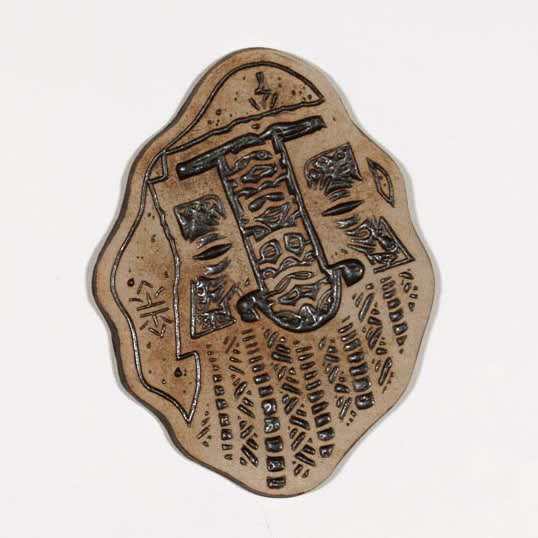 brown slab sculpture depicting abstract symbols and shapes