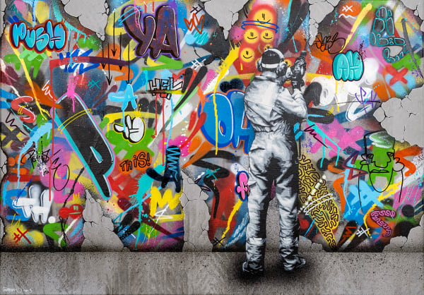 man in black and white drilling into a wall decorated with colorful graffiti
