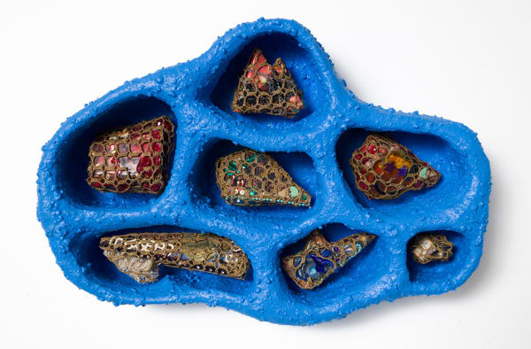 Bright blue tray type object with small sections each holding a small sculptural object