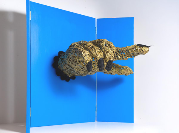 crocheted thread sculpture of a hand mounted on a board