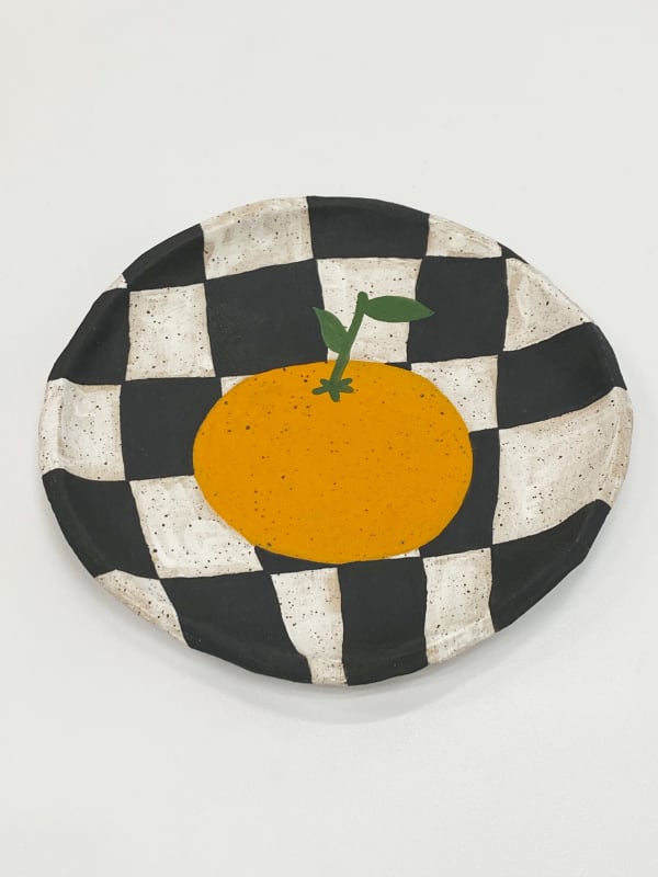 Jackie Brown ceramic plate of orange on black and white checkered background