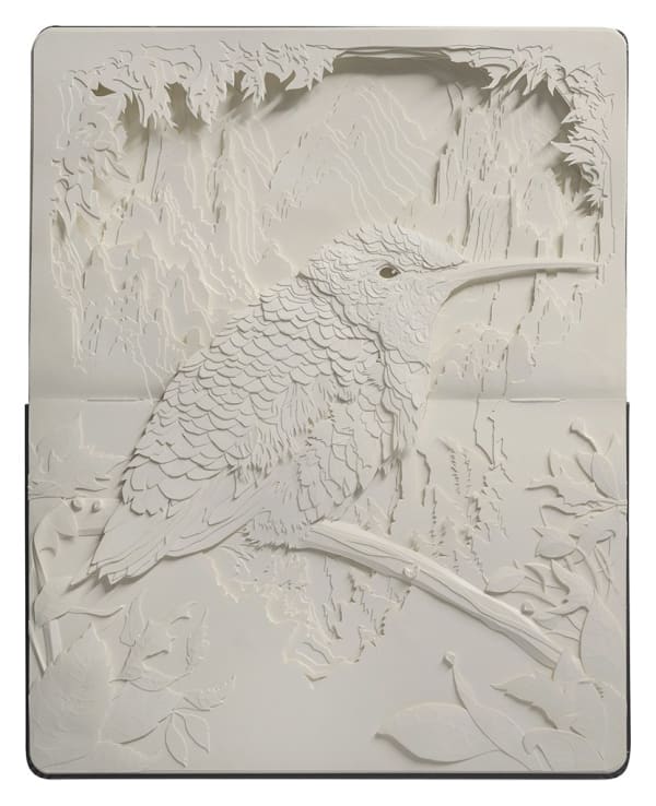 Open face moleskin showing a hummingbird perched on a branch made out of cut paper by artist Brian Mashburn