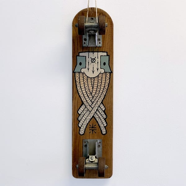 A vintage wood skateboard with a painted image of a masculine face with a beard woven into itself.
