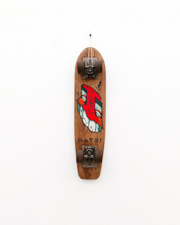 Brown wooden vintage skateboard with a slanted red face GATS character painted on the bottom of the board
