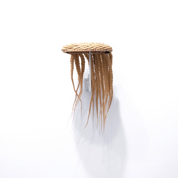 Sculpture made of blonde synthetic hair styled in large braids