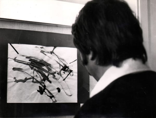 Back of mans head as he looks at painting done by chimpanzee