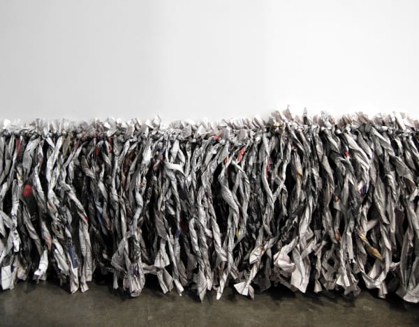 Twisted newspaper strips strung together and lining lower edge of wall touching floor