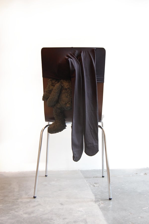 Sculpture similar to a chair with stocking feet and a toy hanging from back