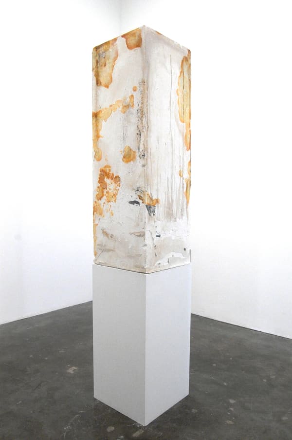 Installation, vertical concrete rectangular tower on pedestal, concrete filled with studio detritus such as tapes, gloves, resin