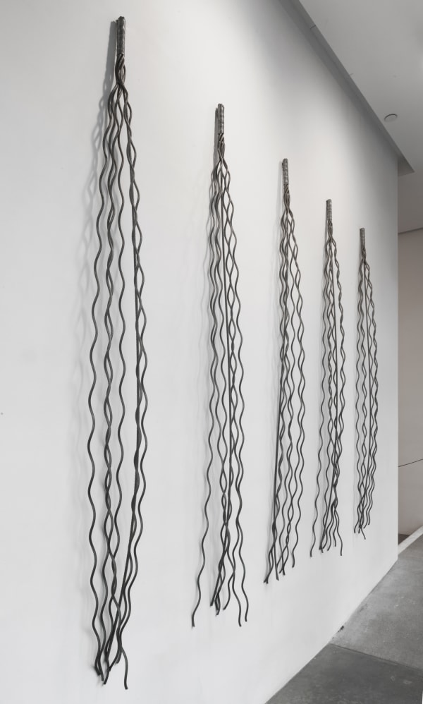 Five bundles of unraveled wire rope and hung at intervals on wall