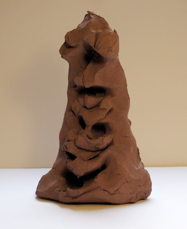 Terracotta sculpture in a triangular shape with faces in it