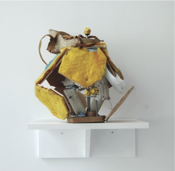 A sculpture on a shelf with panels of felt and other detritus