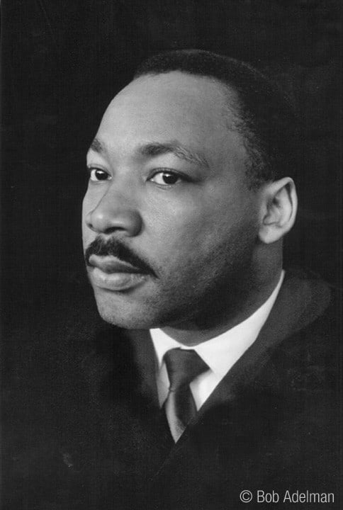 Black & white photograph of Martin Luther King Jr. wearing a black suit and tie, white shirt