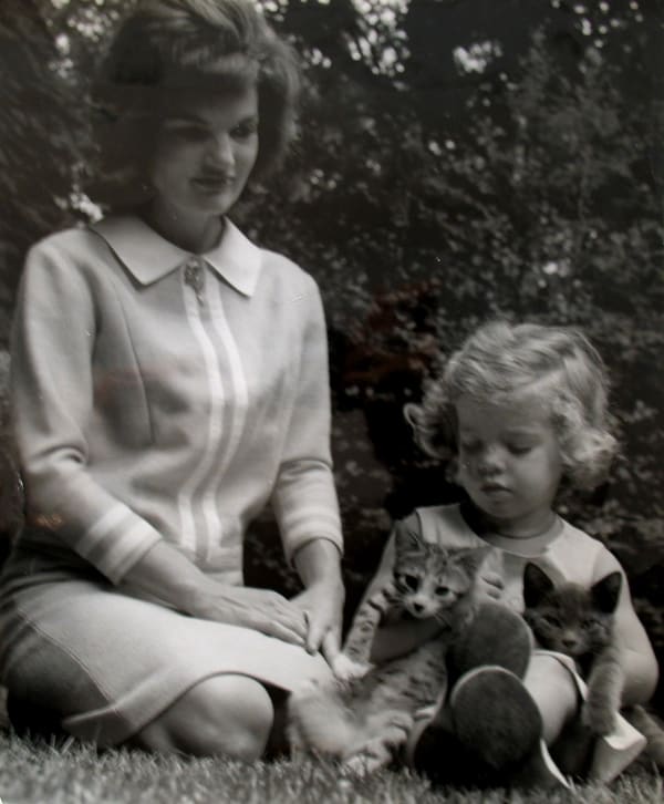 Black and white photograph of Jackie Kennedy and her daughter Caroline holding two kittens on the lawn of their Hyannis Port home