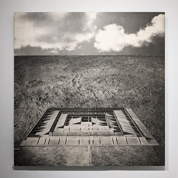 Black and white photomontage of a flat landscape with a three dimensional structure in the form of raised grid lines, viewed from above and at a distance