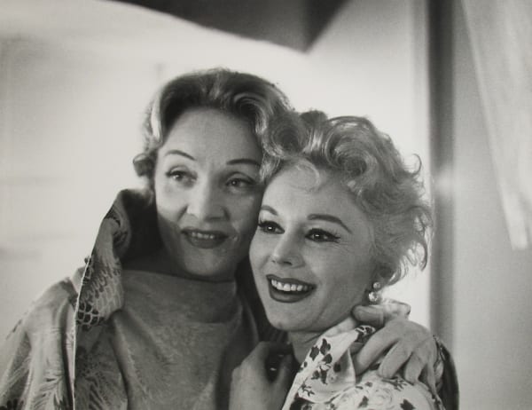 Black and white photograph of actress Marlene Dietrich with her arm around actress Eva Gabor