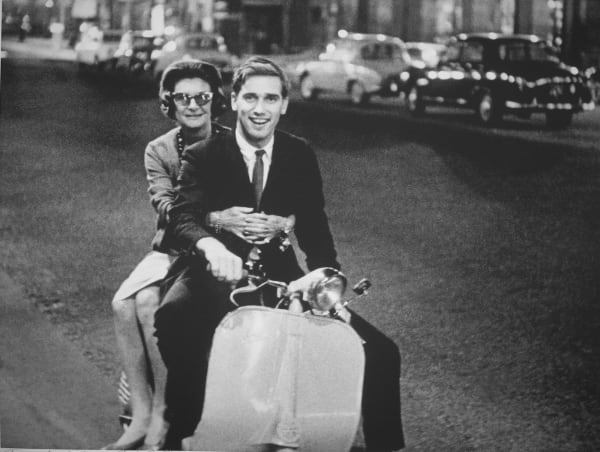 Black and white photograph of Douglas Kirkland and Patricia Carbine, fashion editor at Look magazine on a moped in Paris