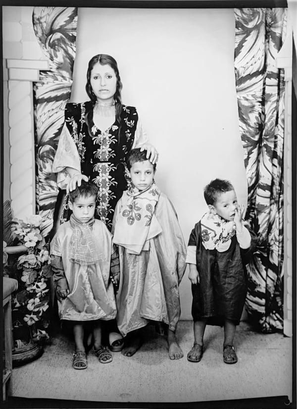 1960s black & white photograph of a mother with three children, in a photography studio