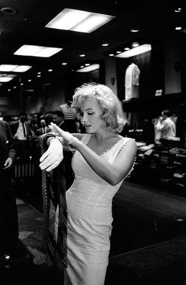 Marilyn Monroe in a white dress checks her wristwatch