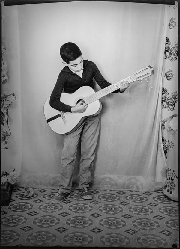 1960s black & white photograph of a child with a guitar, in a photography studio