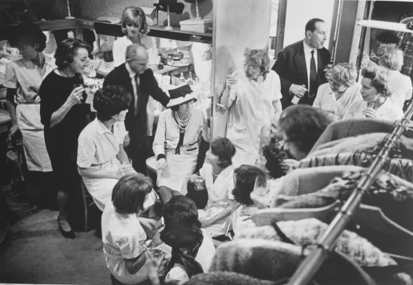 Black and white photograph of Designer Coco Chanel and models in a dressing room after a defile