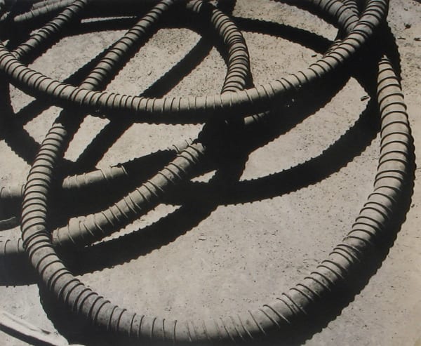 Black and white photograph of a metal coil and the shadows it casts against the ground