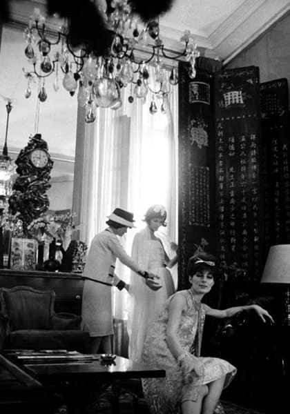 Black and white photograph of Designer Coco Chanel in her private apartment, rue Cambon. In the foreground, one of Chanel's premiere mannequins, Jackie Rogers