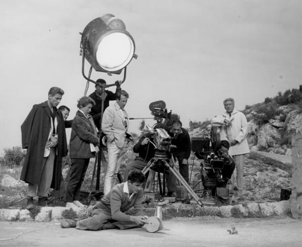 Black and white photograph of Edouard Dermit, Claude Pinoteau and Jean Cocteau filming a scene outside with a large spotlight pointed down over them