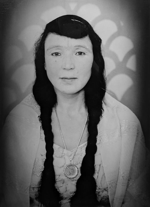 1960s black & white portrait of Amazigh woman with facial tattoos, wearing white dress, in a photography studio