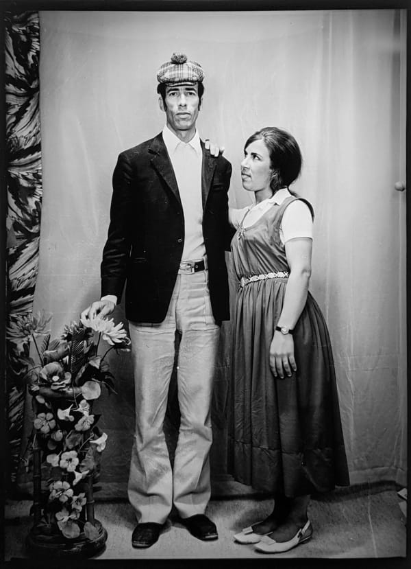 1960s black and white photograph of a woman looking out to the left in profile and a man standing and looking directly at the camera