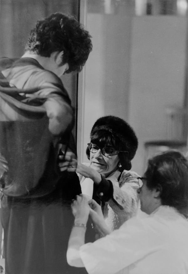 Black and white photograph of Coco Chanel pinning a dress and kneeling down at the House of Chanel Atelier