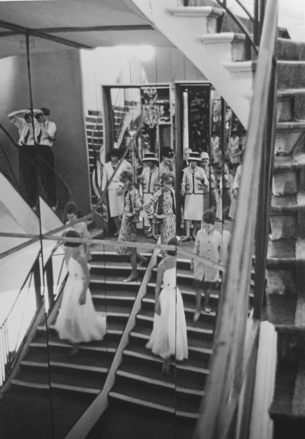 Black and white photograph of models descending a staircase at the House of Chanel