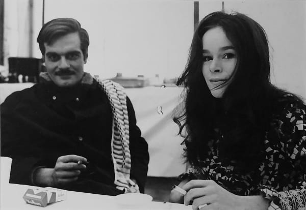 Black and white photograph of Omar Sharif and Geraldine Chaplin, sitting and smiling at the camera, taking a break on the set of “Doctor Zhivago.”
