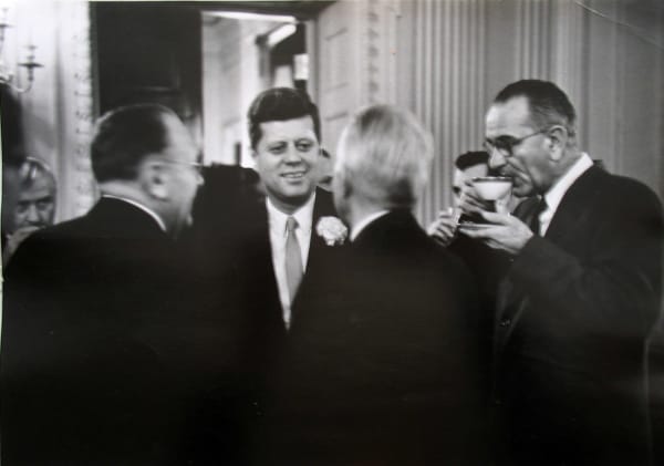 Black and white photograph of John F Kennedy speaking with politicians