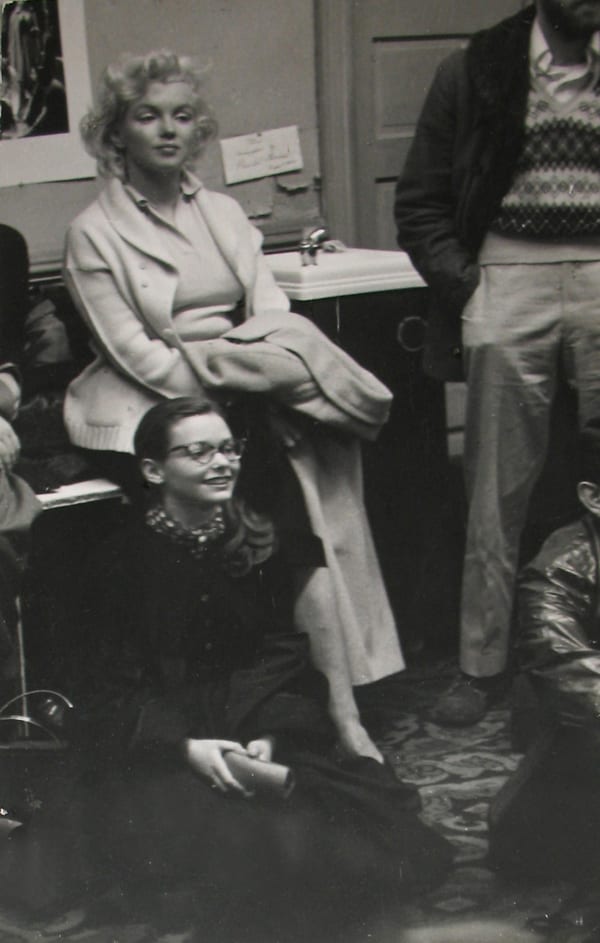 Black and white photograph of Marilyn Monroe sitting in the Actor's Studio with Susan Strasberg seated on the floor next to her