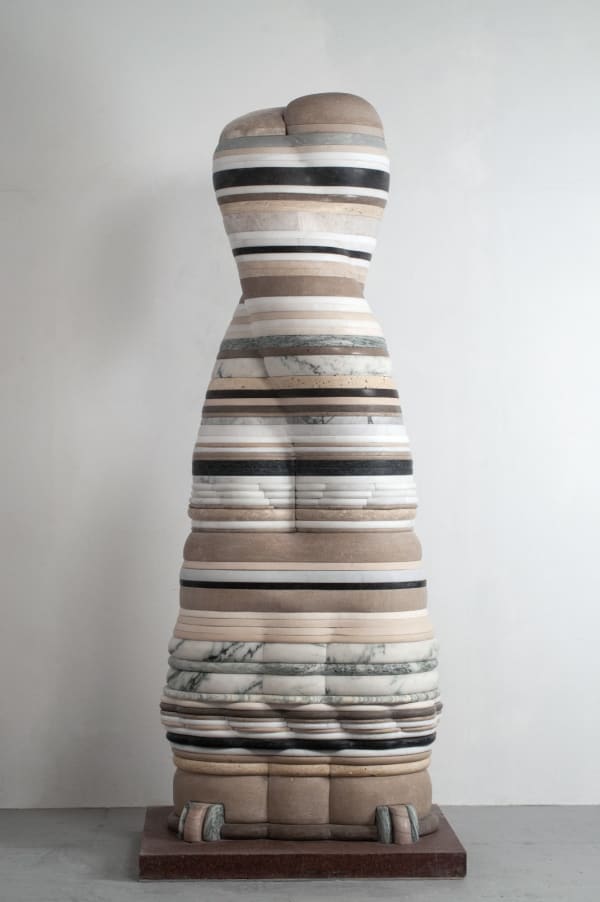 A sculpture of an abstract organic form comprised of thin layers of marble and limestone with two small abstracted "feet" at its base