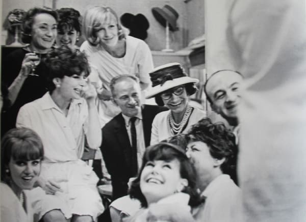Black and white photograph of Designer Coco Chanel and models celebrating