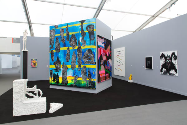 Installation view at the fair. Gray walls and works scattered among them. Many large paintings are shown.